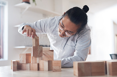 Buy stock photo Man in office with wood block game, thinking challenge and design innovation for balance and construction. Engineering, architecture and asian designer with building blocks for problem solving games.