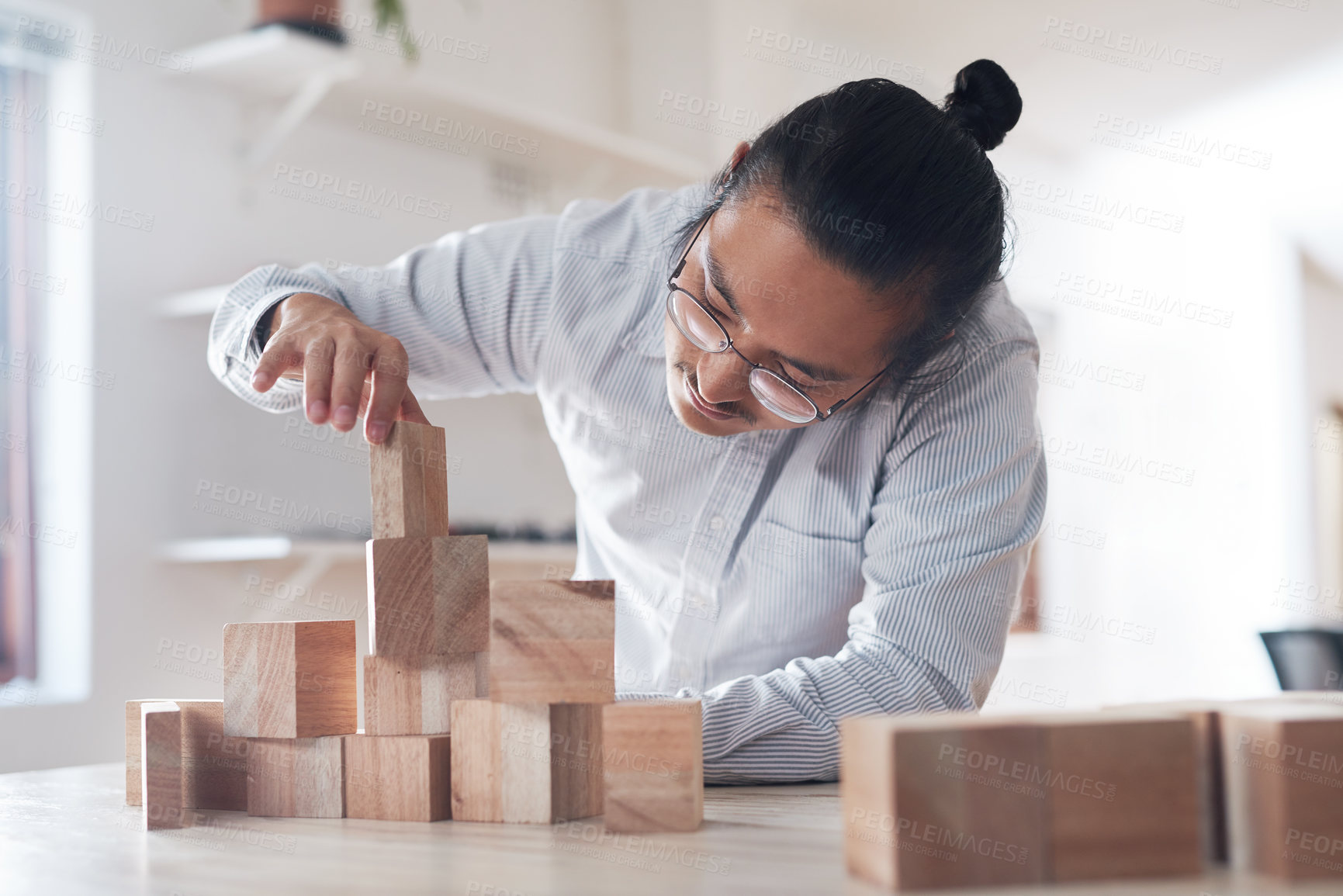 Buy stock photo Man in office with wood block game, thinking challenge and design innovation for balance and construction. Engineering, architecture and asian designer with building blocks for problem solving games.
