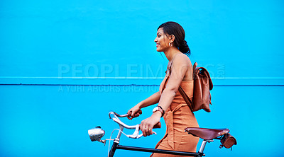 Buy stock photo Shot of an attractive young woman traveling with her bicycle against a blue background