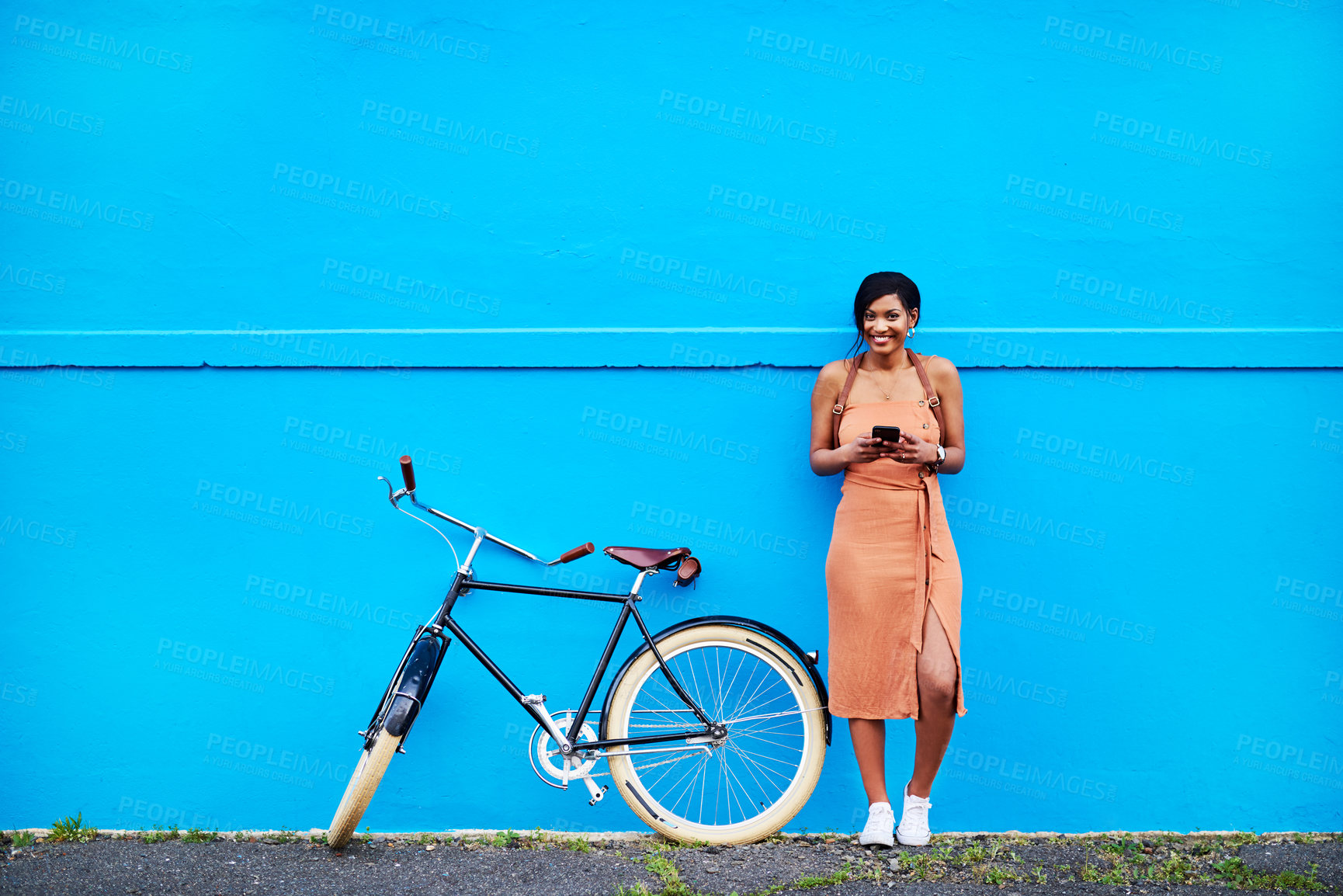 Buy stock photo Full length shot of an attractive young woman using a cellphone while standing next to her bicycle doors