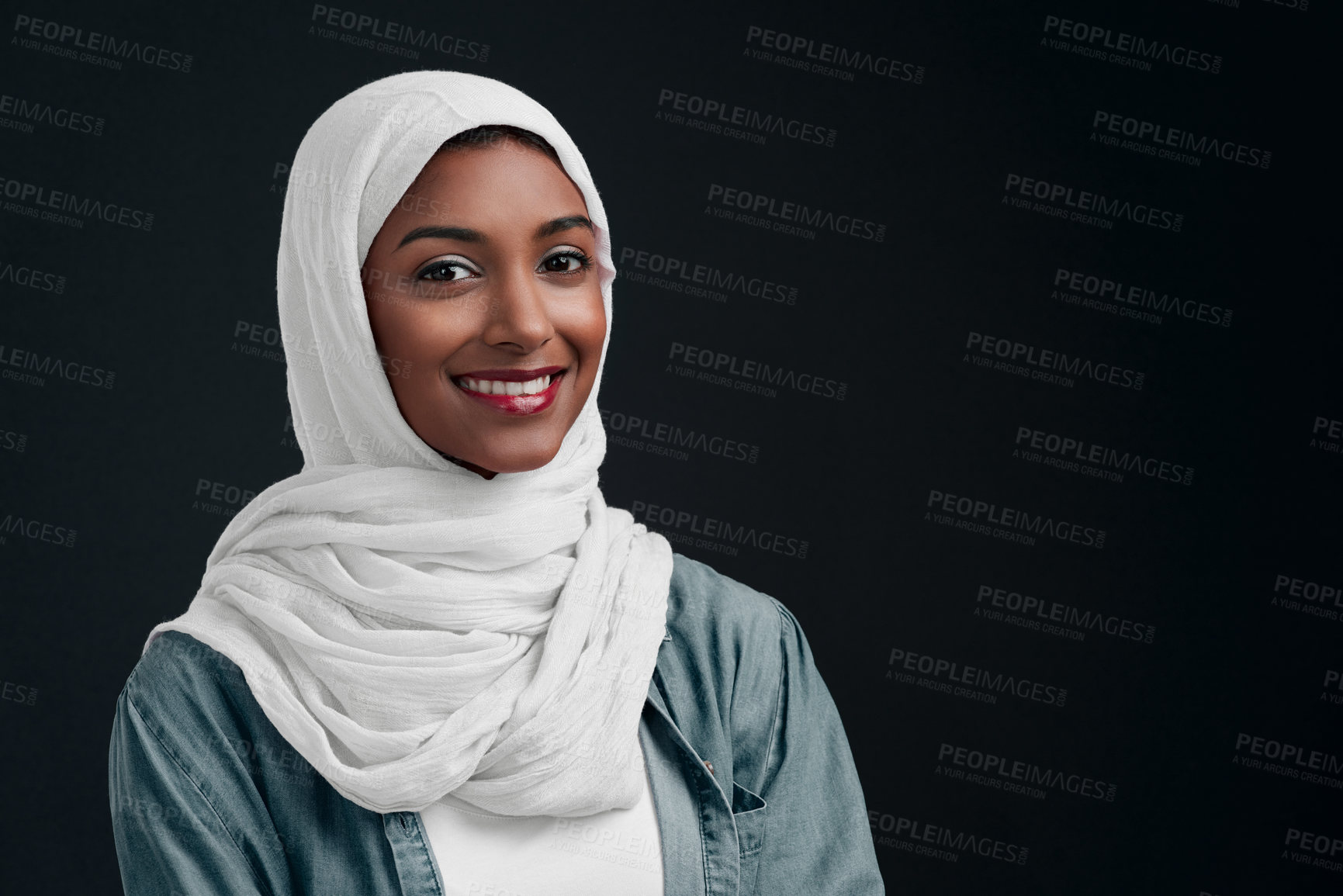 Buy stock photo Cropped shot of an attractive young woman wearing a hijab and standing alone against a black background in the studio
