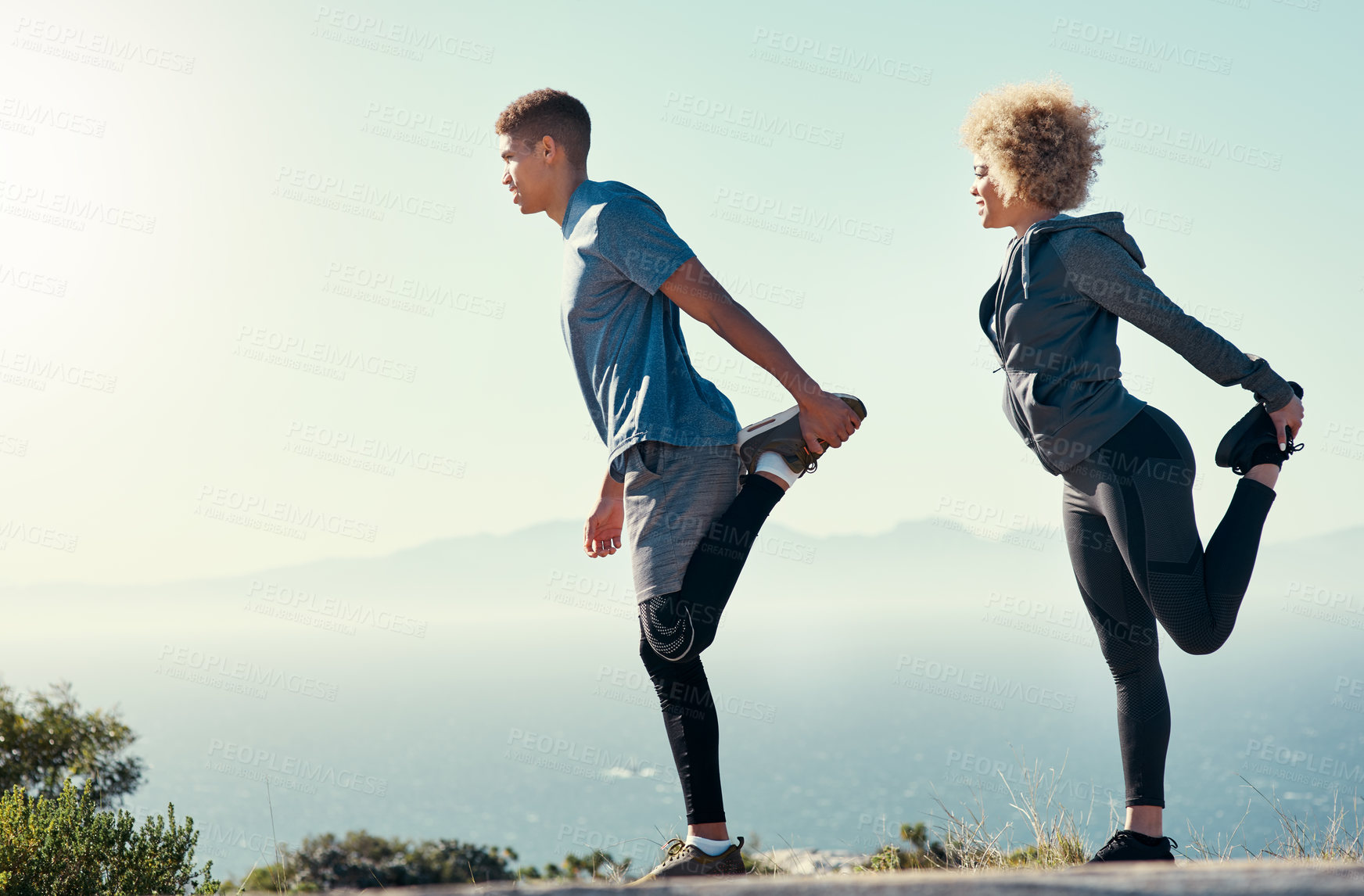 Buy stock photo Shot of a young couple warming up before their run