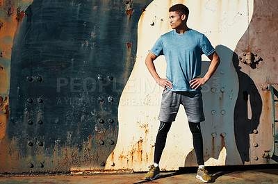 Buy stock photo Shot of a handsome young man posing with his hands on hips while out exercising