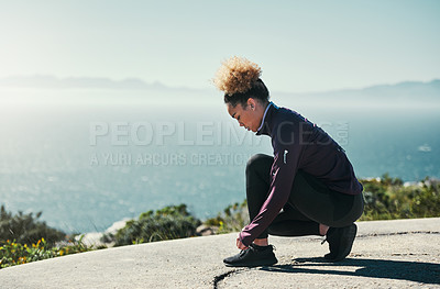 Buy stock photo Shot of a young woman tying her laces while out exercising