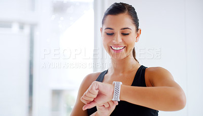 Buy stock photo Shot of an attractive young woman checking the time on her wrist watch while working out at the gym