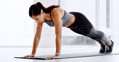 Buy stock photo Full length shot of an attractive young woman doing plank exercises on the floor at the gym