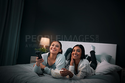 Buy stock photo Women friends on bed at night for movies, eating popcorn and happy sleepover at home with streaming service or television. Gen z people relax in bedroom with TV film, cinema subscription and internet