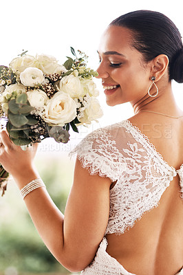 Buy stock photo Shot of a beautiful young bride holding a bouquet of flowers outdoors on her wedding day