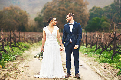 Buy stock photo Full length shot of a happy newlywed young couple walking together outdoors on their wedding day