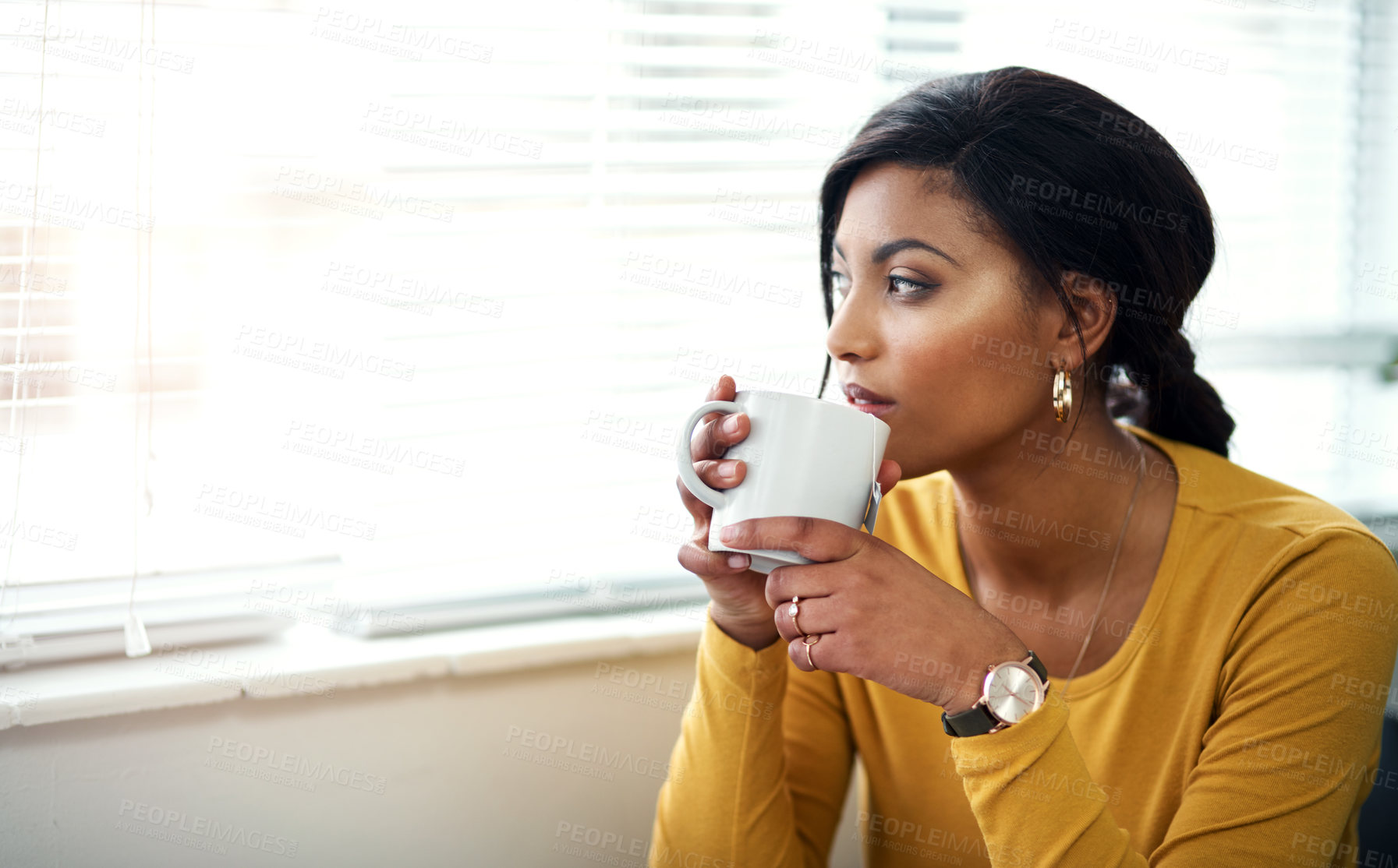 Buy stock photo Cropped shot of an attractive young woman sitting alone and drinking a cup of tea in her home