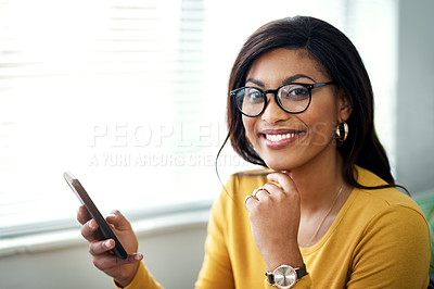 Buy stock photo Cropped shot of an attractive young woman sitting alone and using her cellphone in her home