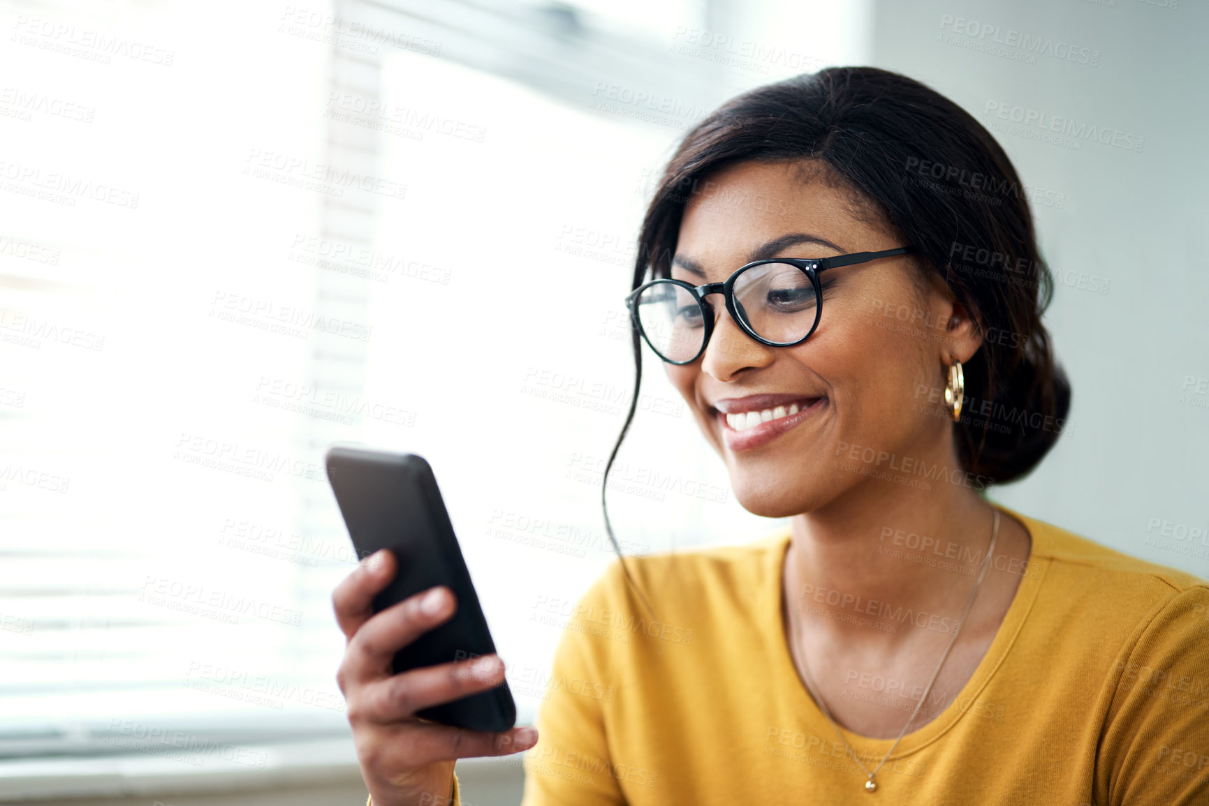 Buy stock photo Cropped shot of an attractive young woman sitting alone and texting on her cellphone in her home