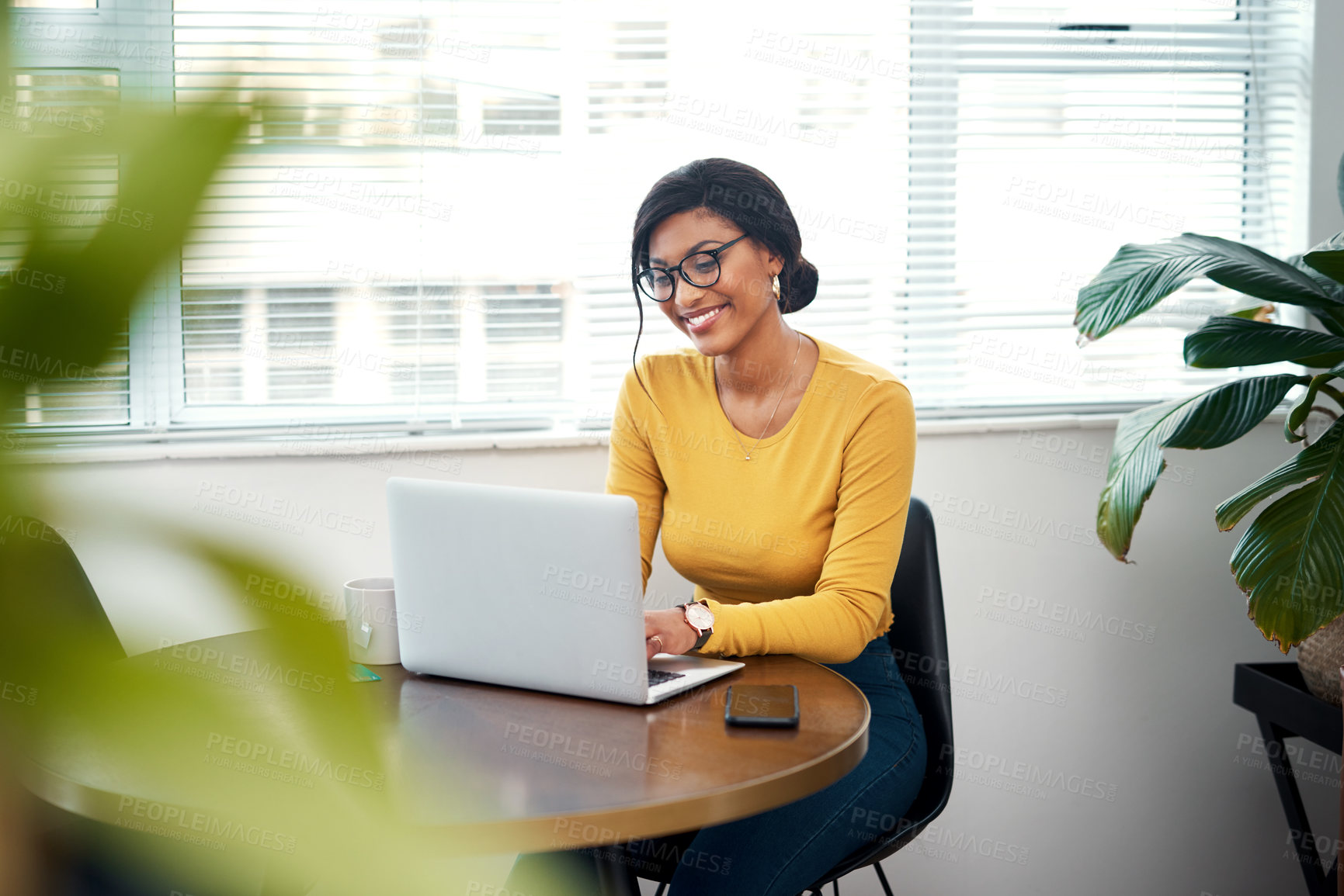 Buy stock photo Cropped shot of an attractive young woman sitting alone in her home and using her laptop