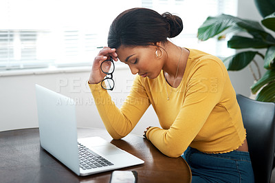 Buy stock photo Cropped shot of an attractive young woman sitting in her home and suffering from a headache while using her laptop