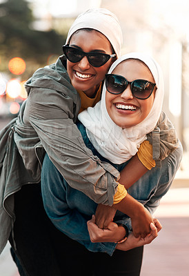 Buy stock photo Islamic woman, friends and piggyback in city with freedom, youth and comic adventure together in street. Muslim women, happy and walking in metro with funny game, sunglasses and support in Qatar