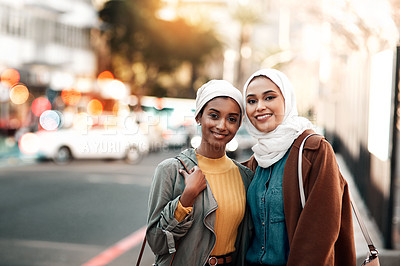 Buy stock photo Cropped shot of two attractive young women wearing headscarves and standing together while touring the city together