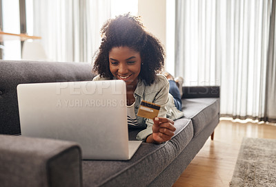 Buy stock photo Shot of a young woman holding her credit card while using her laptop
