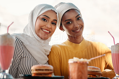 Buy stock photo Cropped portrait of two affectionate young girlfriends having a meal together at a cafe while dressed in hijab