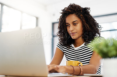 Buy stock photo Cropped shot of an attractive young businesswoman sitting alone in her home and using her laptop
