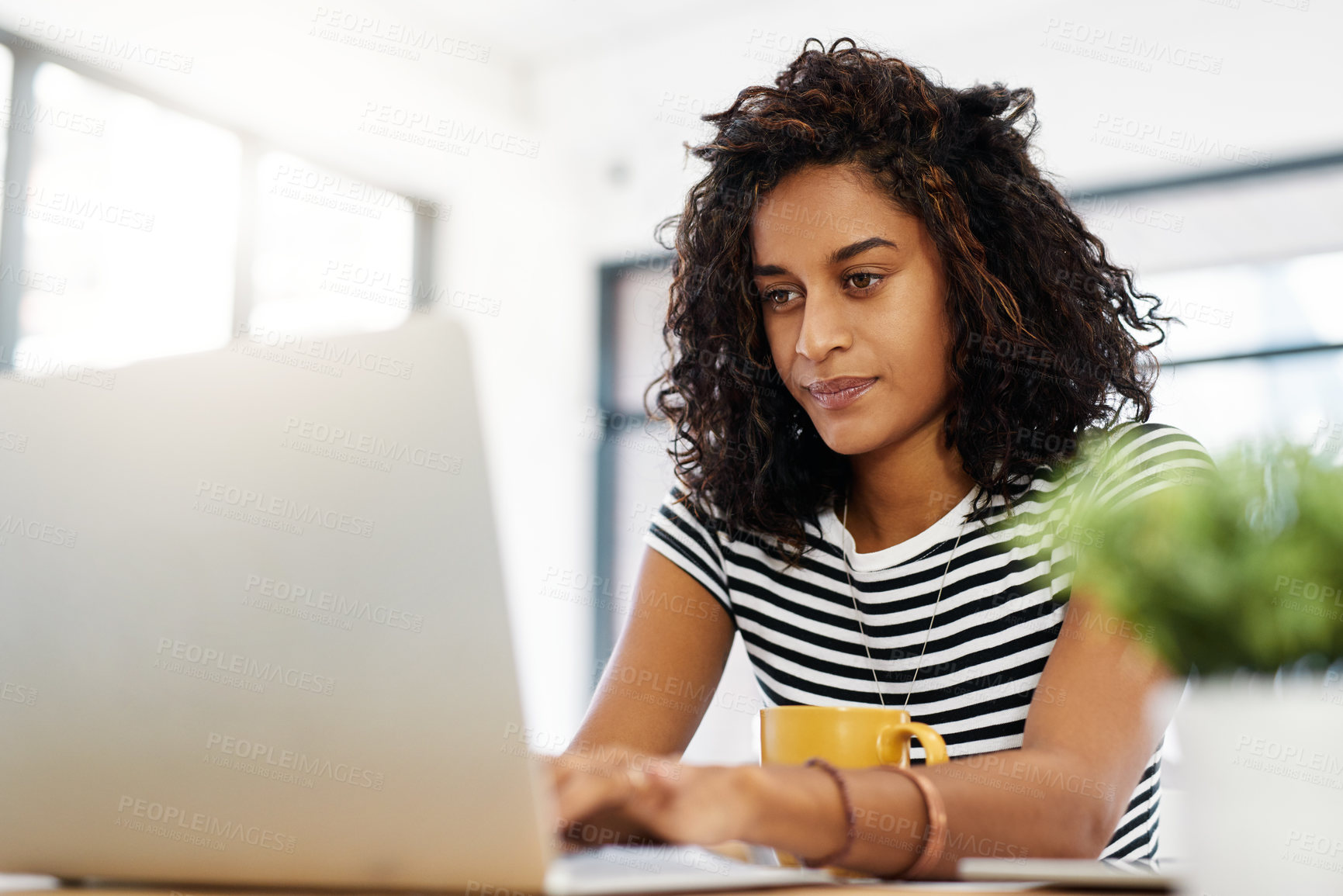 Buy stock photo Cropped shot of an attractive young businesswoman sitting alone in her home and using her laptop