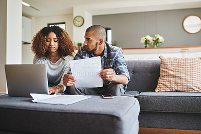 Buy stock photo Cropped shot of a stressed young couple sitting together and using a laptop to go over their financial paperwork