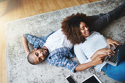 Buy stock photo Cropped shot of an affectionate young couple lying on the floor together and using a laptop in their living room