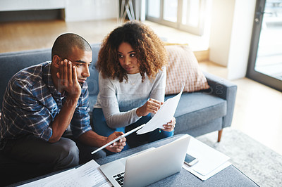 Buy stock photo Cropped shot of a stressed young couple sitting together and using a laptop to go over their financial paperwork