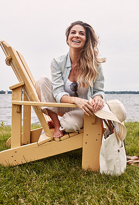 Buy stock photo Shot of a beautiful young woman relaxing on a chair next a lake