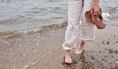 Buy stock photo Cropped shot of an unrecognizable woman going for a walk along the waters edge of a lake