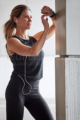 Buy stock photo Shot of a sporty young woman checking her watch while exercising outdoors