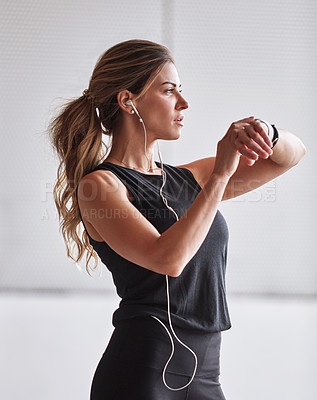 Buy stock photo Shot of a sporty young woman checking her watch while exercising outdoors