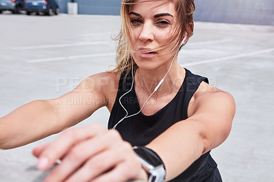 Buy stock photo Portrait of a sporty young woman stretching while exercising outdoors