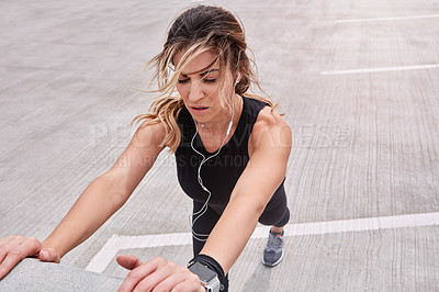 Buy stock photo Shot of a sporty young woman stretching while exercising outdoors