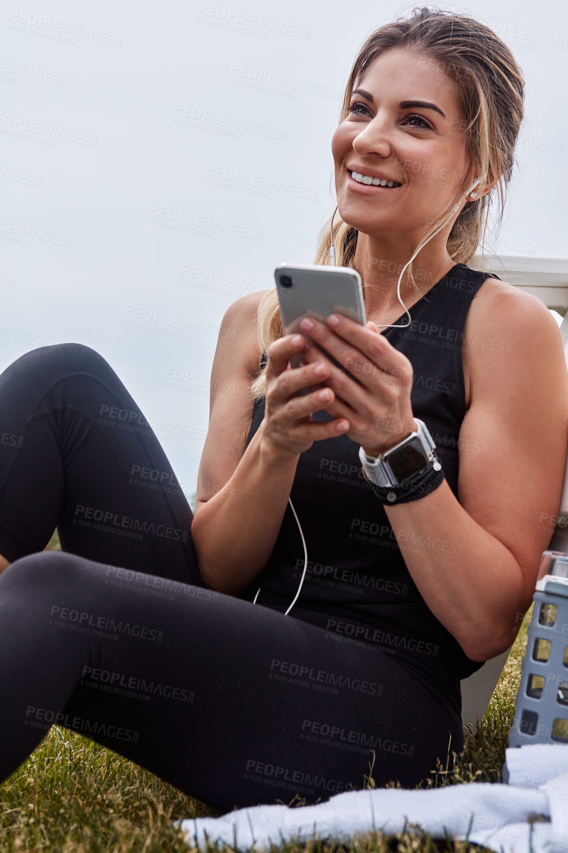 Buy stock photo Shot of a sporty young woman using a cellphone while exercising outdoors