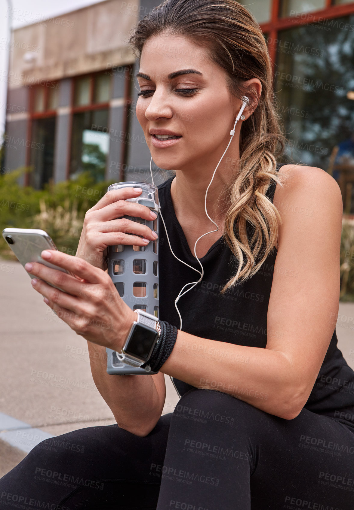 Buy stock photo Shot of a sporty young woman using a cellphone while exercising outdoors