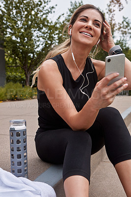 Buy stock photo Shot of a sporty young woman using a cellphone while exercising outdoors