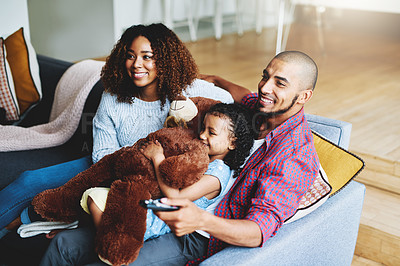 Buy stock photo Cropped shot of a happy young family of three watching tv together in their living room at home