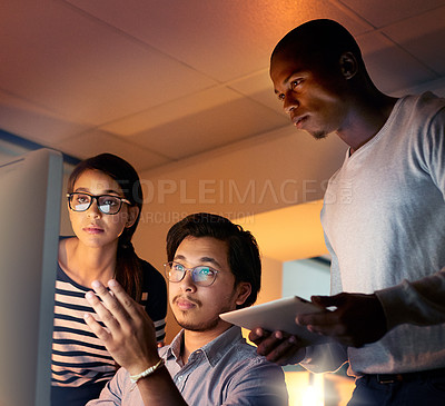 Buy stock photo Shot of colleagues looking at something on a computer while working late at the office