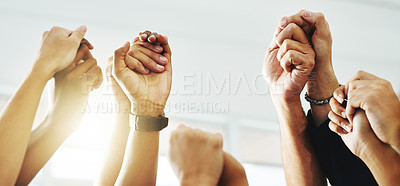Buy stock photo Closeup shot of a group of unrecognizable businesspeople holding hands while raising their arms