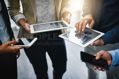 Buy stock photo Cropped shot of an unrecognizable group of businesspeople standing in a circle together and using technology in the office