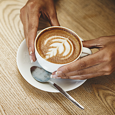 Buy stock photo Cropped shot of an unrecognizable woman sitting alone in a cafe and holding a cup of cappuccino