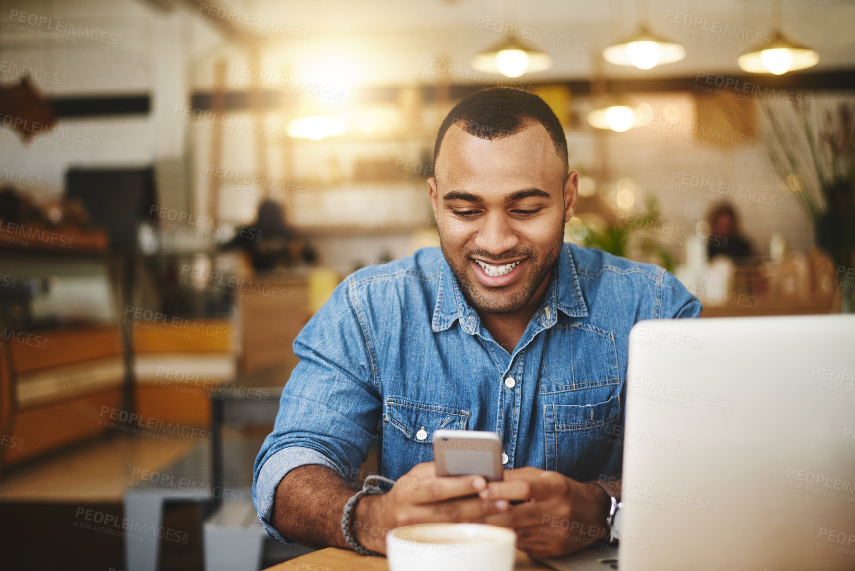 Buy stock photo Cropped shot of a handsome young businessman sitting in a cafe alone and texting on his cellphone