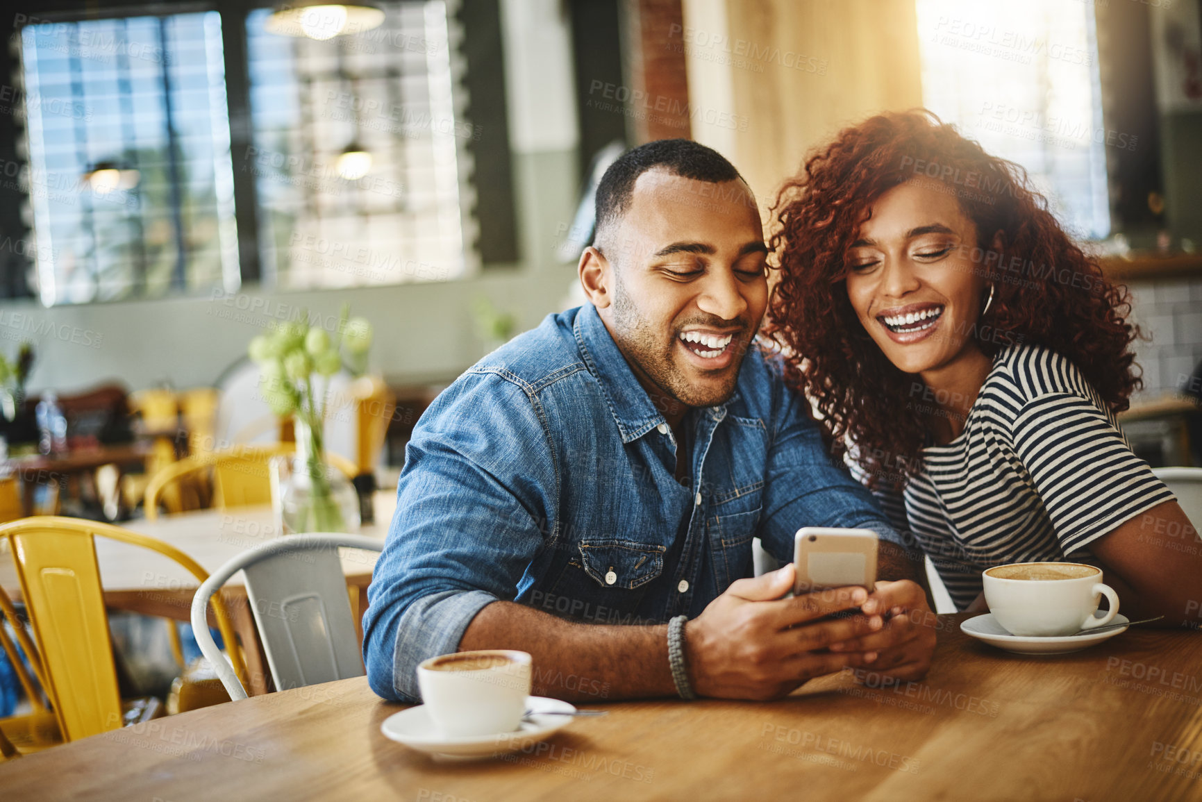 Buy stock photo Cropped shot of a happy young couple sitting together and using a cellphone during a coffee date at a cafe