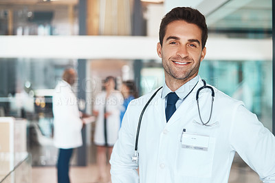 Buy stock photo Portrait of a confident doctor working in a hospital with his colleagues in the background