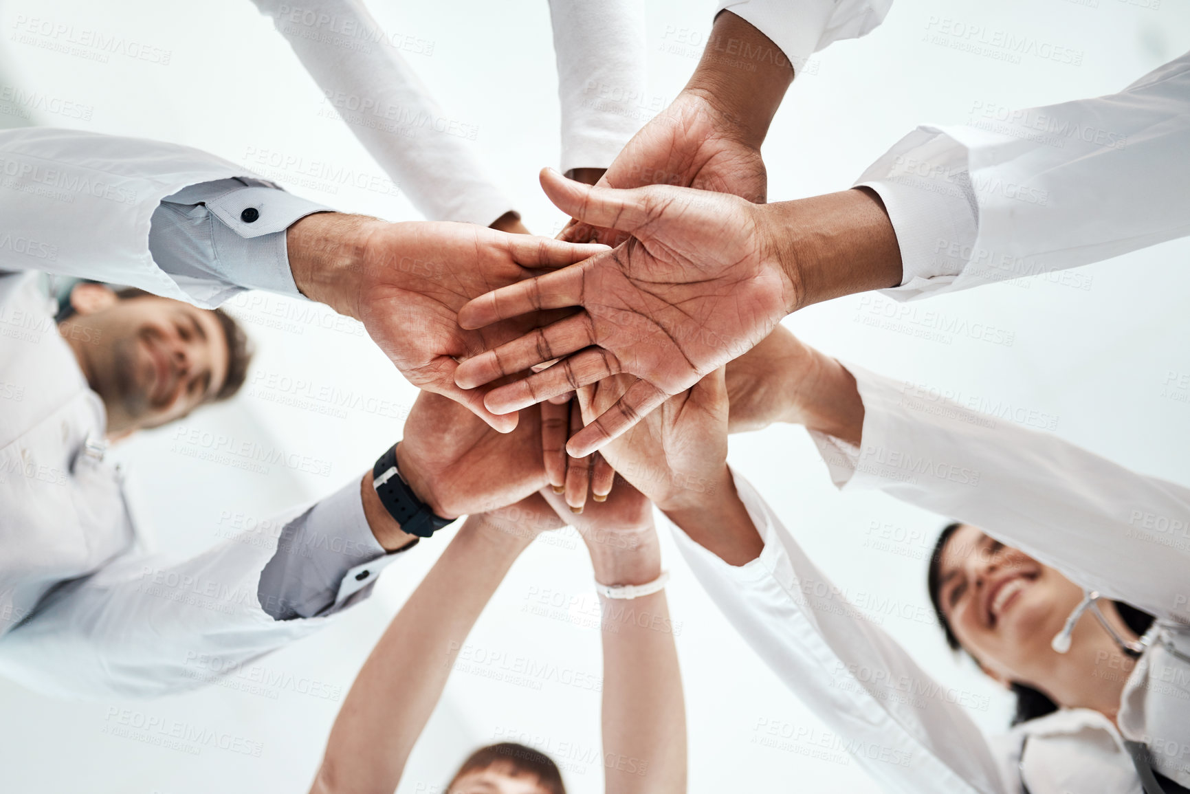 Buy stock photo Low angle shot of a diverse team of doctors joining their hands together in a hospital