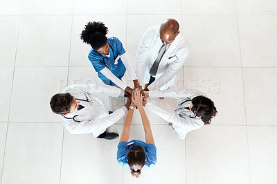 Buy stock photo High angle shot of a diverse team of doctors joining their hands together in a hospital