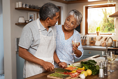 Buy stock photo Shot of a happy mature couple drinking wine while cooking a meal together at home