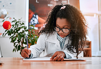 Buy stock photo Shot of an adorable young school girl writing notes in her  note book in science class at school