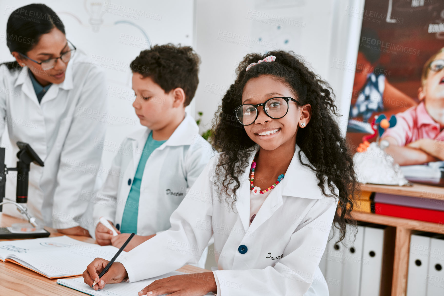 Buy stock photo Portrait of an adorable young school girl writing notes in science class with her teacher and classmate in the background