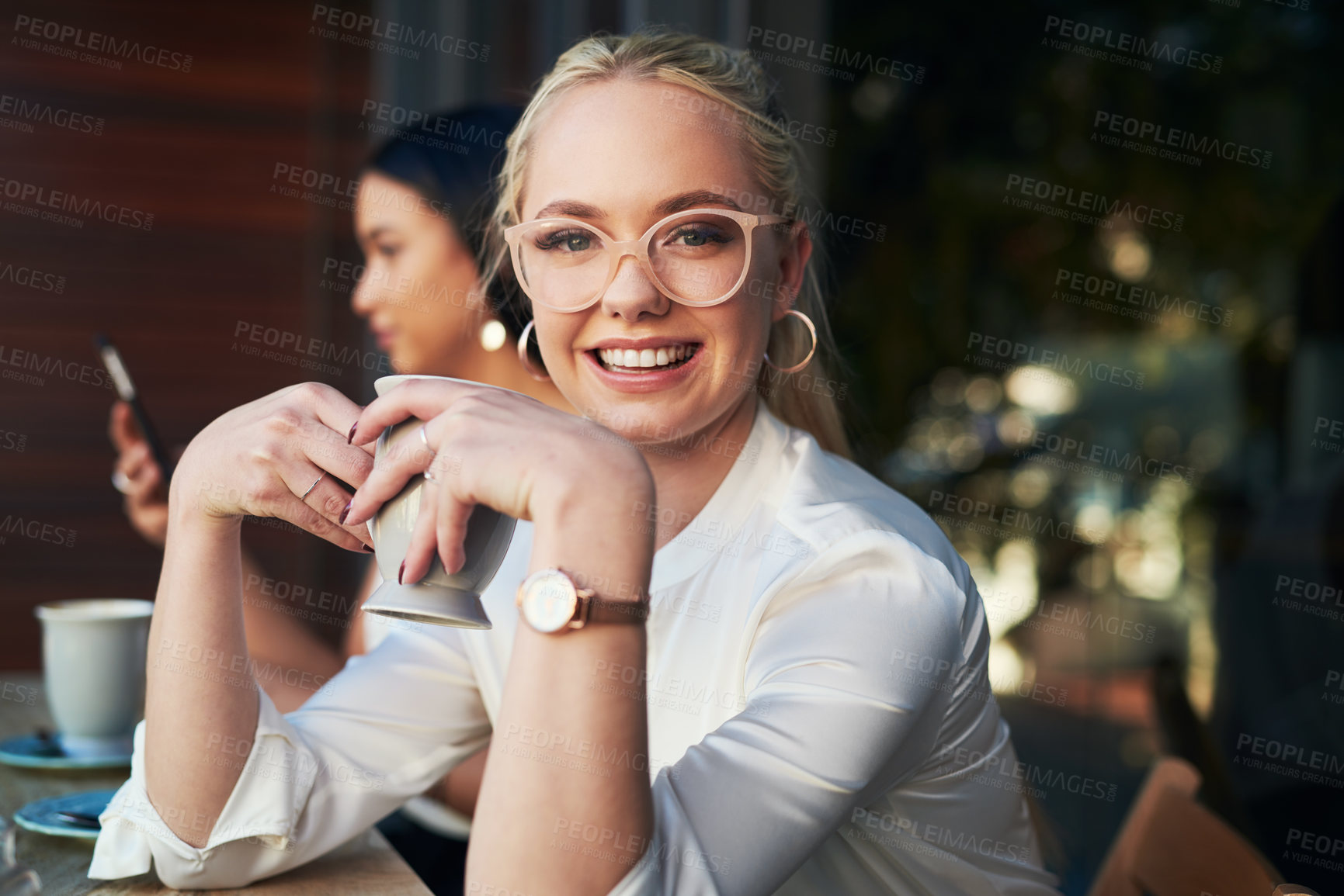 Buy stock photo Defocused shot of a young woman enjoying a cup of coffee at a cafe